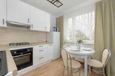 a kitchen with a table and chairs and a white kitchen at Comfortable Apartment with Balcony in Krakow by Rent like home in Kraków