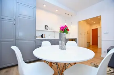 a white dining room with a white table and white chairs at Elegant apartment in the perfect location in Kraków