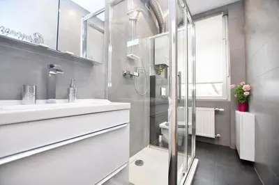 a white bathroom with a shower and a sink at Elegant apartment in the perfect location in Kraków