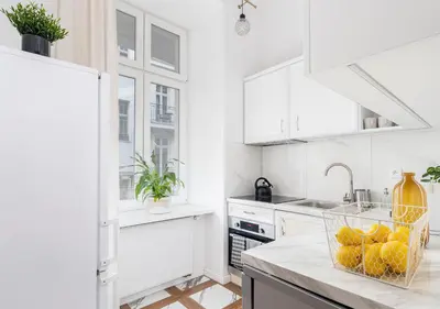 a white kitchen with a basket of fruit on a counter at Malila Premium Apartments City Center Kazimierz Starowiślna 41 in Kraków