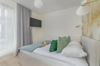 a bedroom with a bed with green and white pillows at Cozy Apartment Orawska with Balcony by Noclegi Renters in Kraków