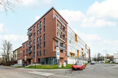 a red car parked in front of a brick building at Cozy Apartment Orawska with Balcony by Noclegi Renters in Kraków