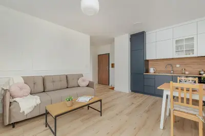 a living room with a couch and a kitchen at Cozy Apartment Orawska with Balcony by Noclegi Renters in Kraków