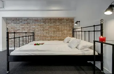 a bedroom with a black bed with a brick wall at Zamkowa15 Apartments in Kraków