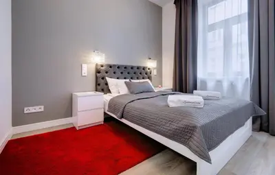 a bedroom with a large bed and a red rug at Zamkowa15 Apartments in Kraków