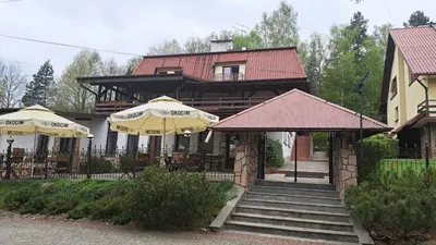 a house with two umbrellas and stairs in front of it at Zajazd-restauracja Zyga in Iwkowa