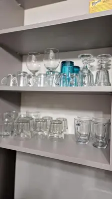 a shelf filled with glass jars and glasses at Underground Cave Apartment in Wieliczka