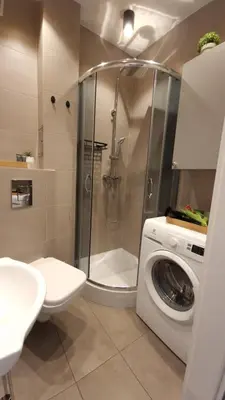 a bathroom with a shower and a washing machine at Underground Cave Apartment in Wieliczka