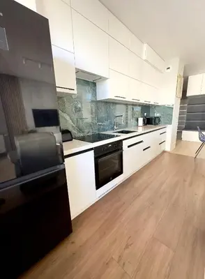 a kitchen with white cabinets and a black refrigerator at Mimosa Kraków Apartment in Kraków