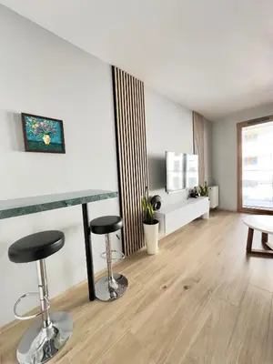 a living room with two bar stools and a table at Mimosa Kraków Apartment in Kraków