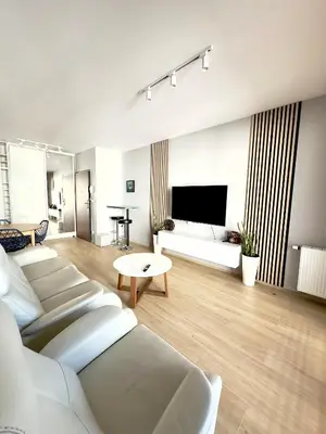 a living room with white furniture and a flat screen tv at Mimosa Kraków Apartment in Kraków
