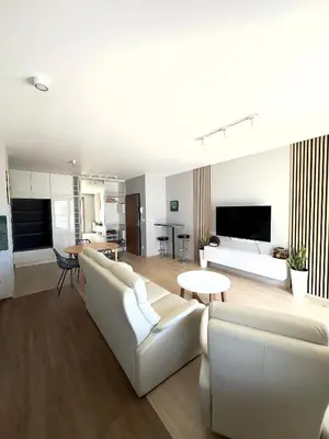 a living room with white couches and a living room with a table at Mimosa Kraków Apartment in Kraków