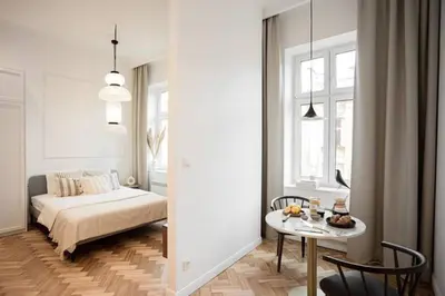 a white bedroom with a bed and a table at Pędzichów Old Town Apartments in Kraków