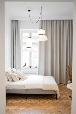 a white bedroom with a bed and two hanging lights at Pędzichów Old Town Apartments in Kraków
