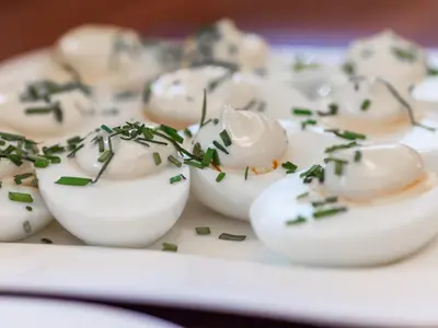 a plate of deviled eggs with green onions on it at Hotel Miodowa in Kraków