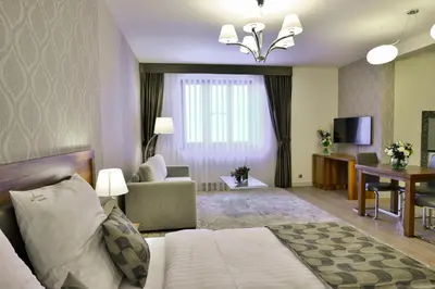 a hotel room with a bed and a living room at Hotel Miodowa in Kraków