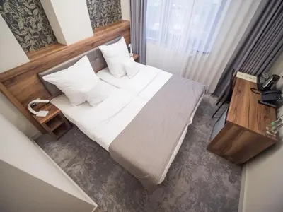 a bedroom with a bed with white sheets and pillows at Hotel Miodowa in Kraków