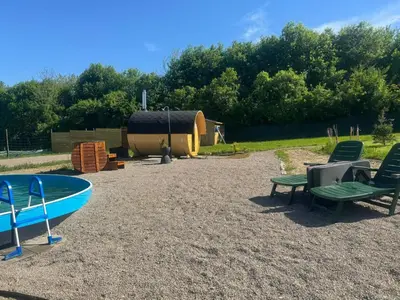 a beach with a boat and chairs and a hut at Glamping Pogorzany - Jurty in Zabierzów