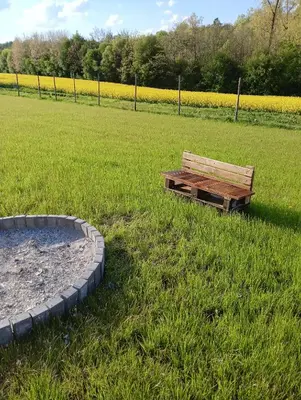 a wooden bench sitting in a field of grass at Glamping Pogorzany - Jurty in Zabierzów