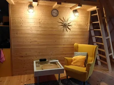 a room with a chair and a clock on a wall at Glamping Pogorzany - Jurty in Zabierzów