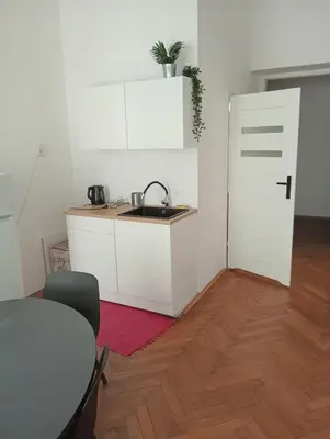 a kitchen with a sink and a table and a door at Apartament Batorego in Kraków