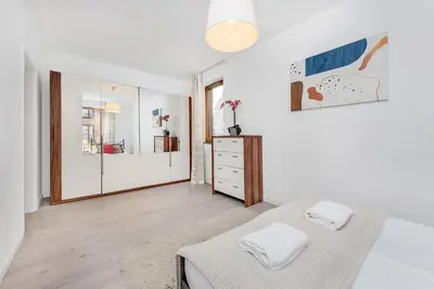 a white bedroom with a bed and a mirror at Old Town Apartment Browar Lubicz Krakow in Kraków