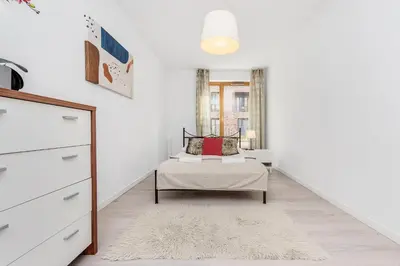 a white living room with a couch and a window at Old Town Apartment Browar Lubicz Krakow in Kraków