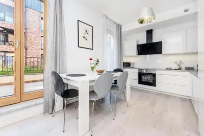 a kitchen and dining room with a white table and chairs at Old Town Apartment Browar Lubicz Krakow in Kraków