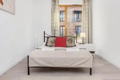 a white bedroom with a bed with red pillows at Old Town Apartment Browar Lubicz Krakow in Kraków