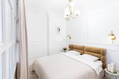 a white bedroom with a large bed with white sheets at Floriańska Old Town Apartments in Kraków