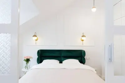 a bed with a green headboard in a white bedroom at Floriańska Old Town Apartments in Kraków