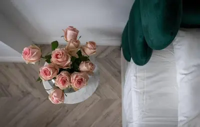 a bouquet of pink roses in a white vase at Floriańska Old Town Apartments in Kraków