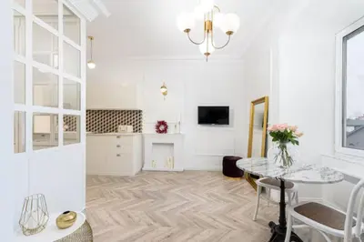 a white living room with a table and a kitchen at Floriańska Old Town Apartments in Kraków