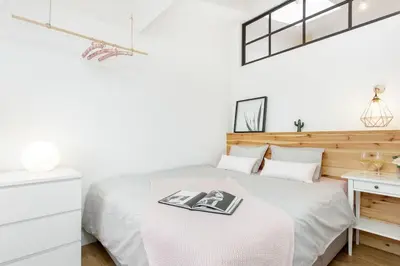 a white bedroom with a bed with a book on it at Radziwiłłowska Old Town Apartments in Kraków