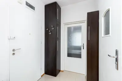 a hallway with white walls and a black door at Borkowska Comfort Apartment by BookingHost in Kraków