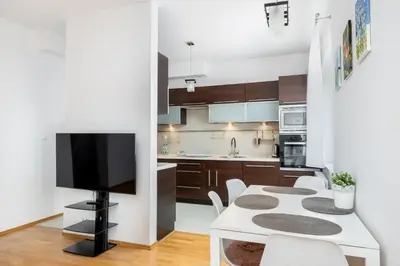a kitchen with a white table and a tv at Borkowska Comfort Apartment by BookingHost in Kraków