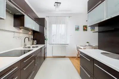 a kitchen with brown cabinets and white counter tops at Borkowska Comfort Apartment by BookingHost in Kraków