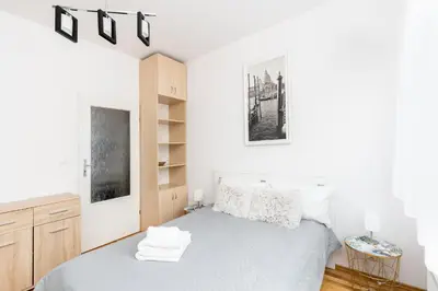 a white bedroom with a bed and a shelf at Borkowska Comfort Apartment by BookingHost in Kraków