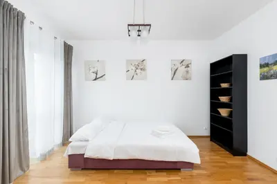 a white bedroom with a bed and a black cabinet at Borkowska Comfort Apartment by BookingHost in Kraków