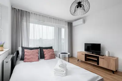 a white bedroom with a bed and a tv at Prokocim Kosocicka Apartment by BookingHost in Kraków