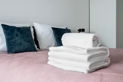 a pile of white towels sitting on a bed at Prokocim Kosocicka Apartment by BookingHost in Kraków