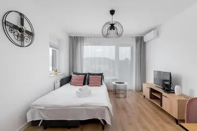 a white bedroom with a bed and a tv at Prokocim Kosocicka Apartment by BookingHost in Kraków
