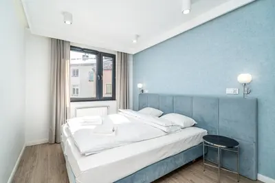 a bedroom with a large bed and a blue wall at RentPlanet - Apartament Dębniki in Kraków
