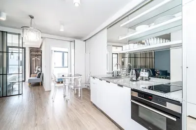 a kitchen with white cabinets and a table with chairs at RentPlanet - Apartament Dębniki in Kraków
