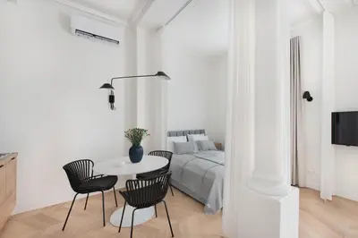 a white bedroom with a bed and a table and chairs at Apartament Kazimierz Mostowa in Kraków