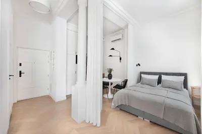 a white bedroom with a bed and a table at Apartament Kazimierz Mostowa in Kraków