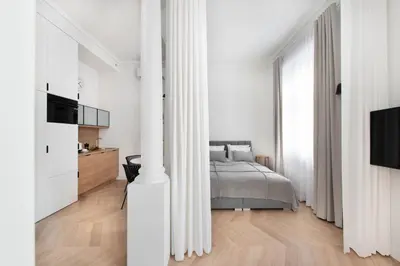 a white bedroom with a bed and a tv at Apartament Kazimierz Mostowa in Kraków