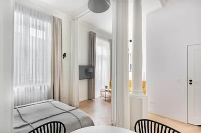 a white bedroom with a bed and two chairs at Apartament Kazimierz Mostowa in Kraków
