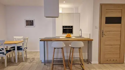 a kitchen with a counter with stools and a table at Perfect Location Comfort Apartment City Beat#10 in Kraków