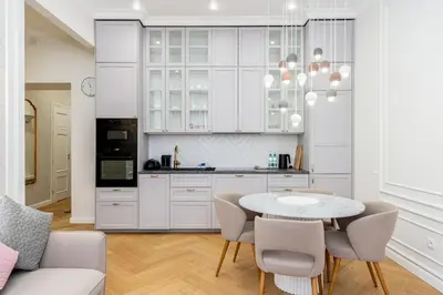 a kitchen with white cabinets and a table and chairs at Vistula River Deluxe Apartment by BookingHost in Kraków